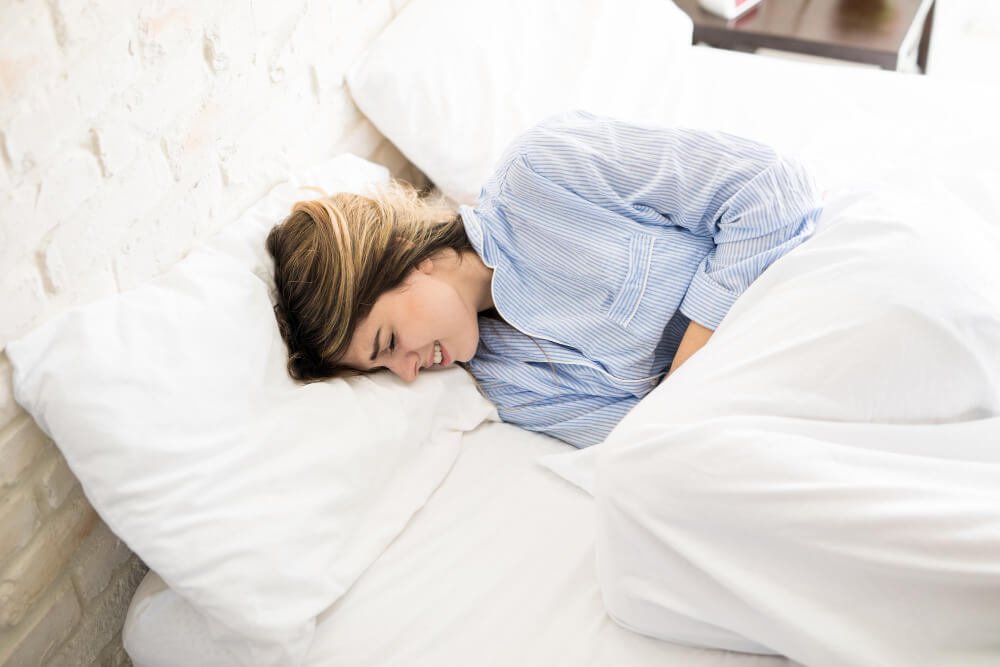 young woman staying in bed with major pains